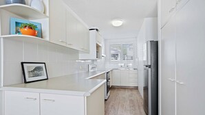 A modern kitchen with white cabinetry, a built-in oven, and a refrigerator. - Goodwin Towers 10, Burleigh Heads. (Gold Coast)