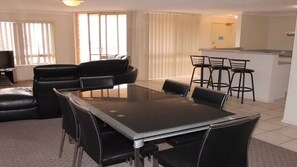 Relax in this stylish living space with a central dining table, comfortable leather chairs, and a large window offering a view.