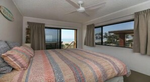 Relax in this serene beachfront room with a large bed and stunning ocean views through the window and sliding glass door.