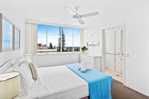 Relax in this serene hotel room with a large bed, ceiling fan, and city views.