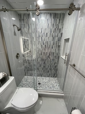 Ein modernes Badezimmer mit einer Duschkabine, einer Toilette und einem Waschbecken.