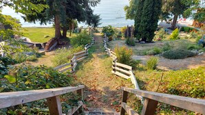 Un escalier en bois mène à un espace jardin offrant une vue sur l’eau.