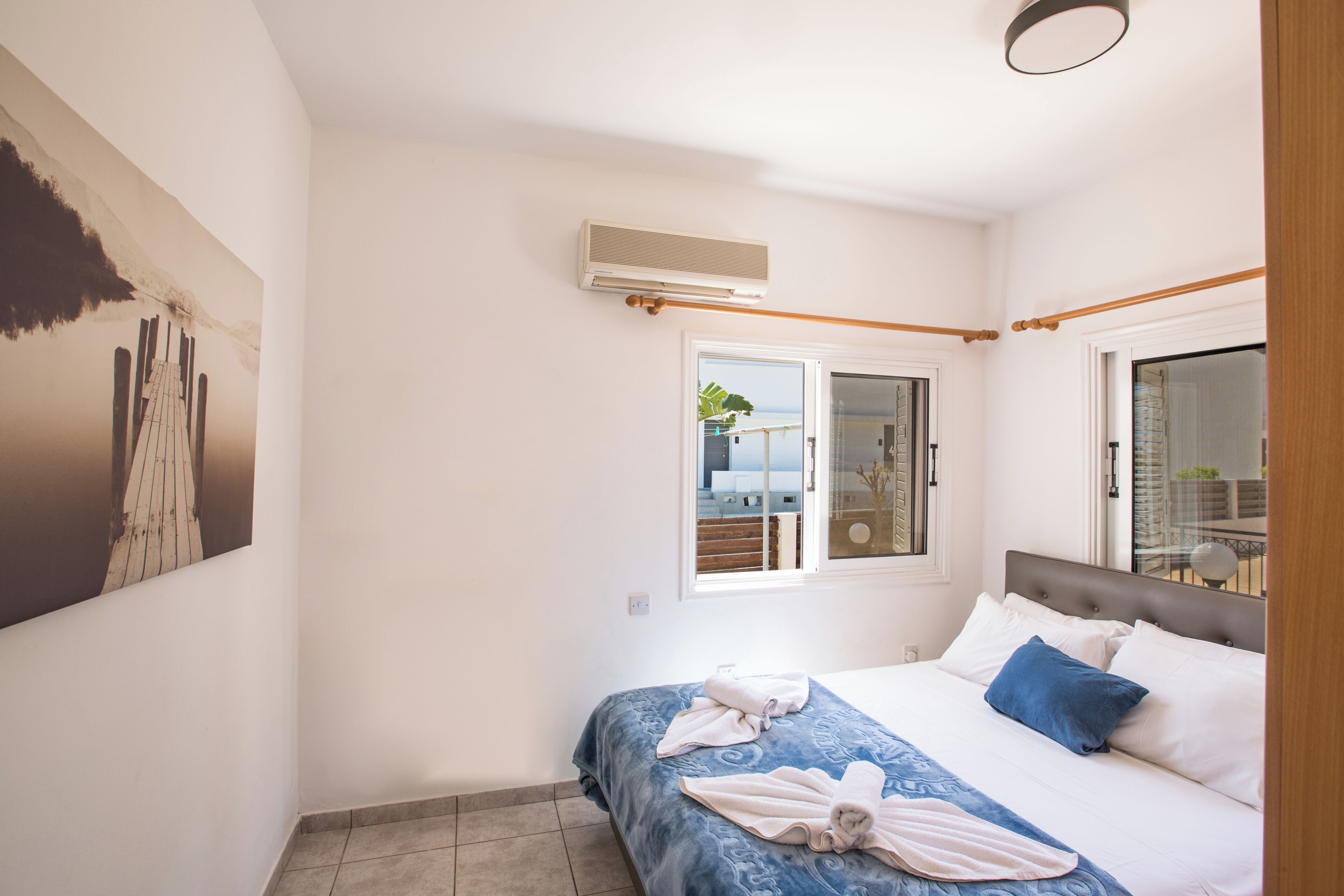 Un dormitorio con cama, ventana y equipo de aire acondicionado.