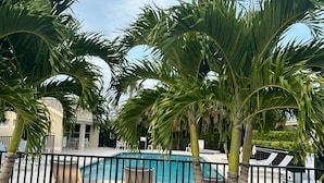A pool area with palm trees, lounge chairs, and a building in the background. - Exclusive Lely Resort House -Private Pool -Sleeps 6 (Naples)