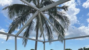 A covered patio with a table and chairs, overlooking a body of water and palm trees. - Exclusive Lely Resort House -Private Pool -Sleeps 6 (Naples)