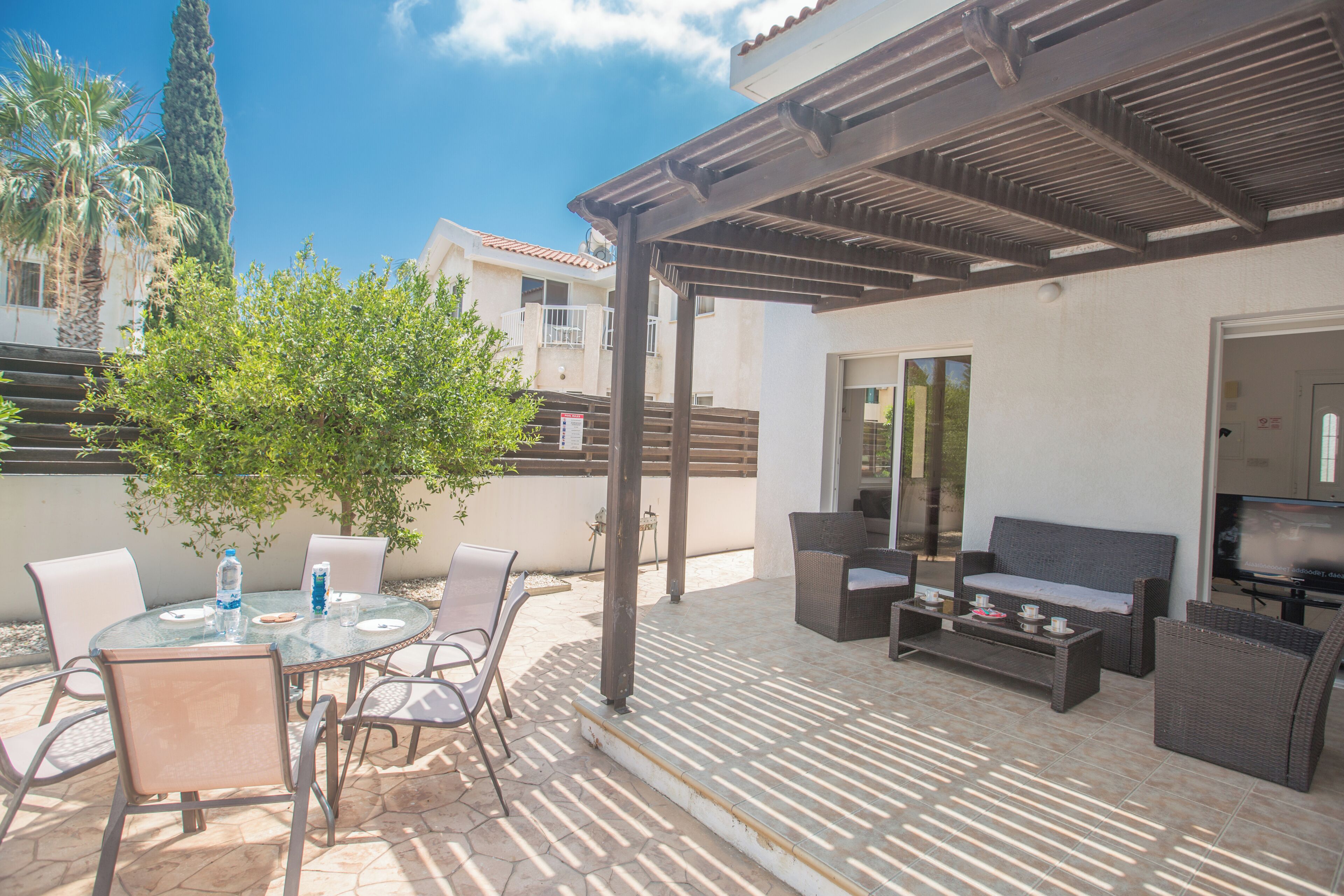 An outdoor patio area with a round table, chairs, a sofa, and a TV.