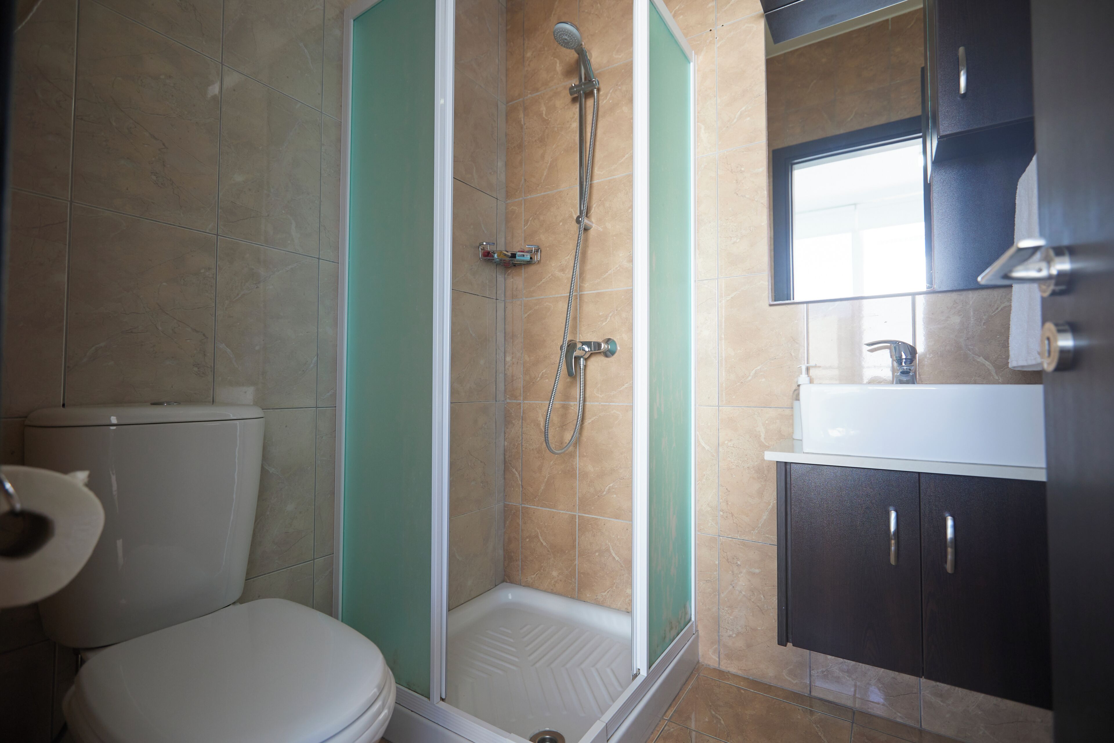 Une salle de bain comprenant des toilettes, un espace douche et un lavabo avec des meubles de rangement.