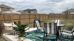 Une terrasse avec des meubles d’extérieur, une plante en pot et un tapis à motifs.