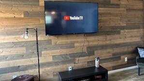 Un téléviseur à écran plat fixé sur un mur en bois, avec le logo de YouTube TV.