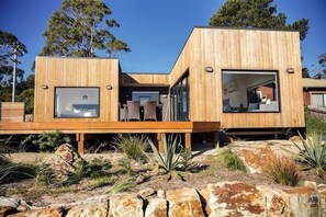 Ett modernt trähus med stora fönster och en veranda.