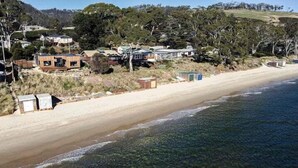 A coastal residential area with houses, a sandy beach, and a clear view of the ocean.