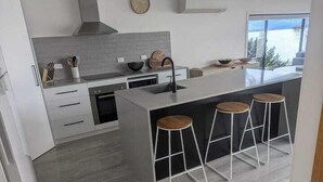 A modern kitchen with a large island, bar stools, and a view of the outdoors.