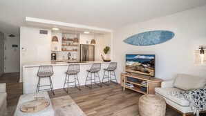 A modern kitchen with a central island, bar stools, and a dining area.