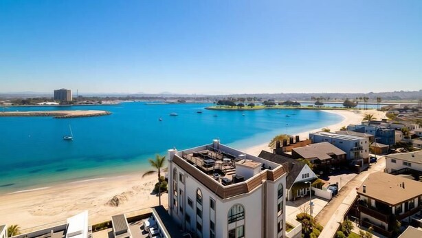 A coastal hotel with a beach view, a pool, and a parking area. - Large Waterfront | Private Roof Deck | Fireworks View (San Diego)