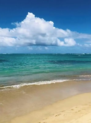 Une plage à l’eau turquoise et limpide, bordée d’un rivage sablonneux.