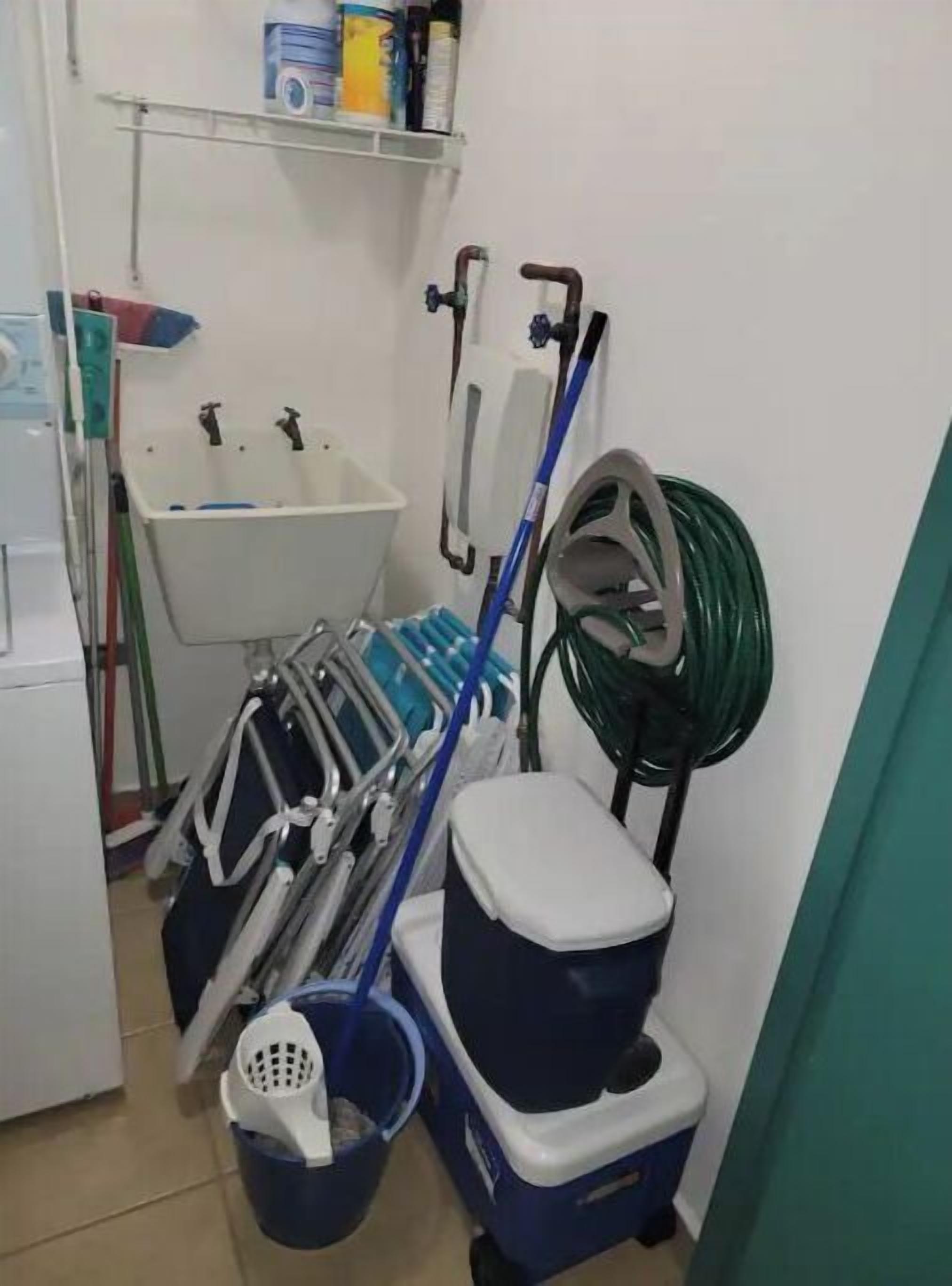 A small, compact bathroom with a sink, a toilet, and a mop and bucket.