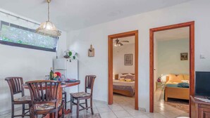 A dining area with a round table and chairs, a ceiling fan, and a window with a view of greenery.
