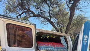 Ein Van mit Bett, Surfbrett und Campingausrüstung.