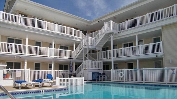 A multi-story hotel with a central swimming pool, balconies on each floor, and a staircase connecting the levels.