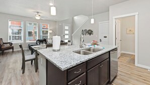 A modern kitchen with granite countertops, a double sink, and dark cabinetry. - Meridian Family Home | King Bed | 4 TVs | Work From Home Setup | Freeway Access (Meridian)