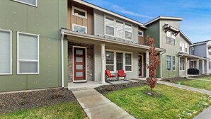 A townhouse with a front porch, two red chairs, and a small tree. - Meridian Family Home | King Bed | 4 TVs | Work From Home Setup | Freeway Access (Meridian)