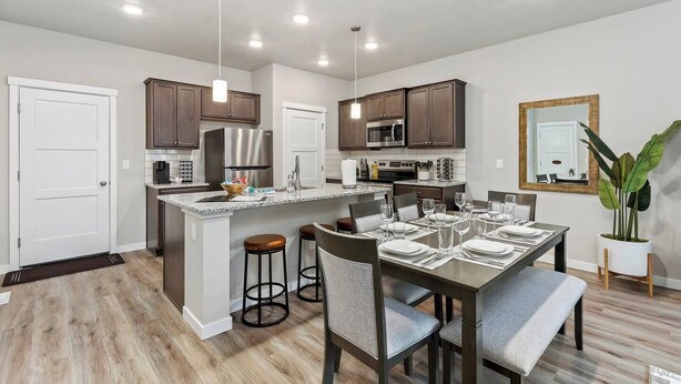 A modern kitchen with dark wood cabinets, stainless steel appliances, and a central island with stools. - Meridian Family Home | King Bed | 4 TVs | Work From Home Setup | Freeway Access (Meridian)