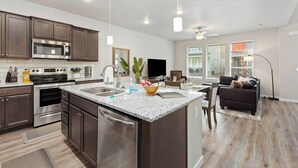 A modern kitchen with granite countertops, stainless steel appliances, and a central island. - Meridian Family Home | King Bed | 4 TVs | Work From Home Setup | Freeway Access (Meridian)