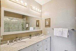 A bathroom with two sinks, a large mirror, and a shower.