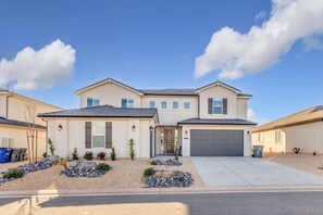 A two-story house with a garage, a front porch, and a landscaped front yard with rocks and small plants.