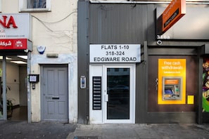 A storefront with a sign for flats 1-10 on Edgware Road, including a contact number.