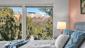 A bedroom with a large window, a bed with pillows, a bedside lamp, and a view of a mountainous landscape. - Best Panoramic Views in Sedona, Hot Tub + Firepit! (Sedona)