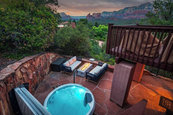 An outdoor patio with a hot tub, seating area, and a view of mountains.