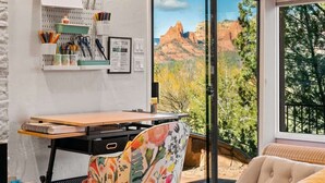 A room with a desk, a chair, a window with a view of red rock formations, and a wall-mounted pegboard with office supplies. - Best Panoramic Views in Sedona, Hot Tub + Firepit! (Sedona)