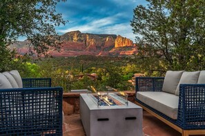 A patio with outdoor furniture, a fire pit, and a scenic view of red rock formations.