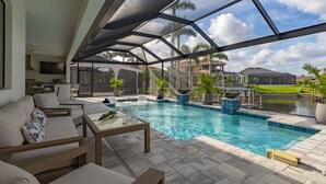 Un espace piscine doté d’un patio couvert, de sièges extérieurs et offrant une vue sur le quartier environnant.