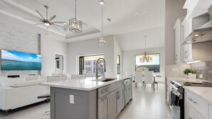 Une cuisine moderne dotée d’un grand îlot central, de meubles blancs et d’appareils électroménagers en acier inoxydable.