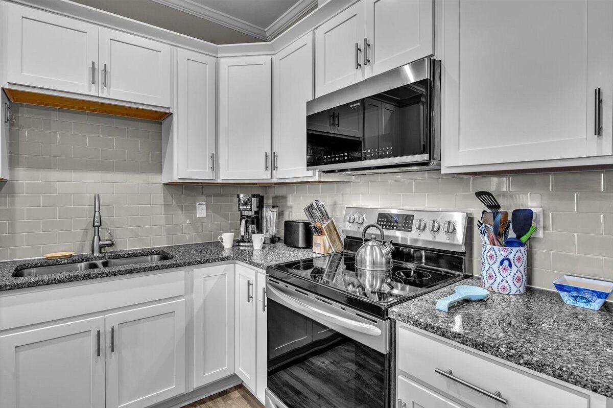 A modern kitchen with white cabinets, a stainless steel microwave, a gas stove, and a built-in oven.