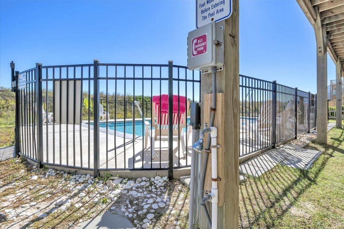 A gated pool area with a sign indicating foot washing before entering the pool.