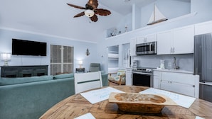 Una sala de estar moderna con una mesa de comedor de madera, un sofá verde y un ventilador de techo.