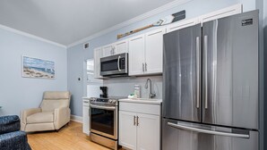 A compact kitchen with a stainless steel refrigerator, microwave, and oven.