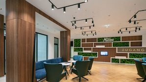 Eine moderne Hotelhalle mit einer Rezeption, einer Sitzecke und holzverkleideten Wänden.