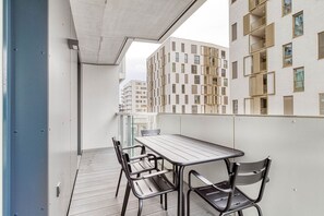 Ein Balkon mit Tisch und Stühlen, der auf ein Gebäude mit einer verzierten Fassade blickt.