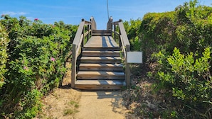 A wooden staircase leading up to a beach area, surrounded by greenery and a clear sky. - Blue Skies - Bright, Spaciuos 4 BR oceanside home w/Private Pool and Hot Tub (Southern Shores)
