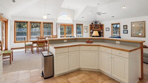 A spacious kitchen with a large island, wooden cabinets, and a dining area with chairs. - Blue Skies - Bright, Spaciuos 4 BR oceanside home w/Private Pool and Hot Tub (Southern Shores)