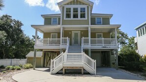 A two-story house with a balcony on the upper floor, a front porch, and a staircase leading to the entrance. - Sound Reflections - 4 BR Soundside home in Monteray Shores Corolla w/Private Pool (Corolla)