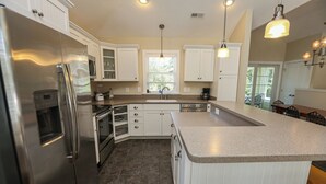 A modern kitchen with white cabinetry, stainless steel appliances, and a granite countertop. - Sound Reflections - 4 BR Soundside home in Monteray Shores Corolla w/Private Pool (Corolla)