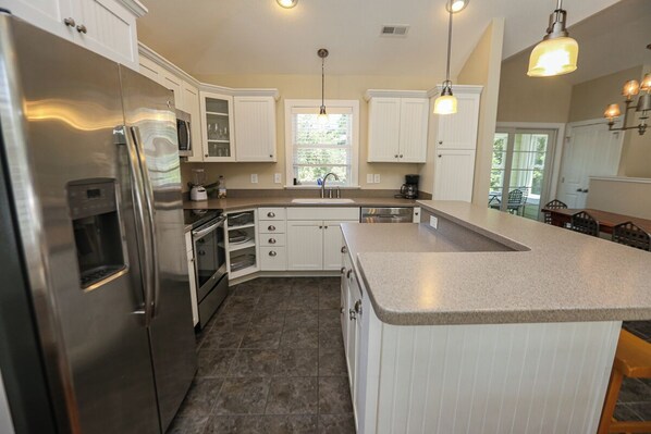 A modern kitchen with white cabinetry, stainless steel appliances, and a granite countertop.