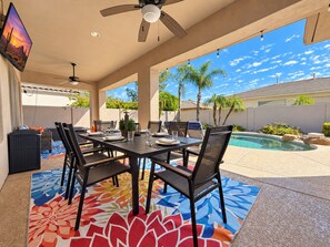 An outdoor patio with a dining table, chairs, and a pool.