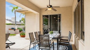 An outdoor patio with a dining table, chairs, and a ceiling fan.