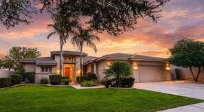A residential house with a well-maintained lawn, a garage, and a driveway.